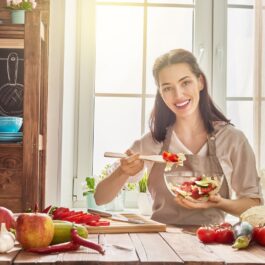 O femeie frumoasă care consumă fructe și legume într-o bucătărie spațioasă