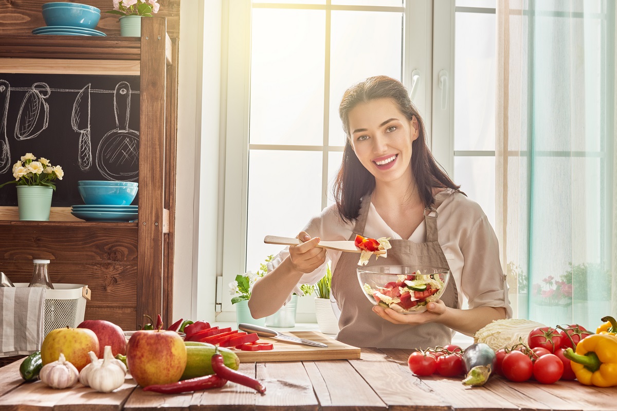 O femeie frumoasă care consumă fructe și legume într-o bucătărie spațioasă