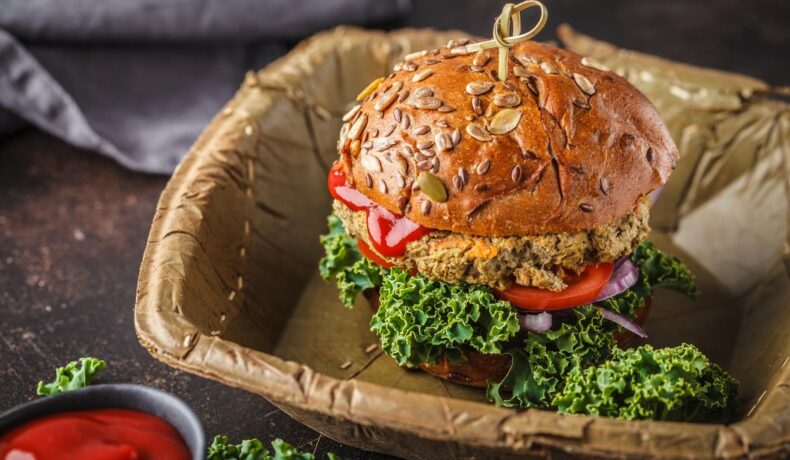 Un burger vegan din linte, într-un coș cu un sos alături