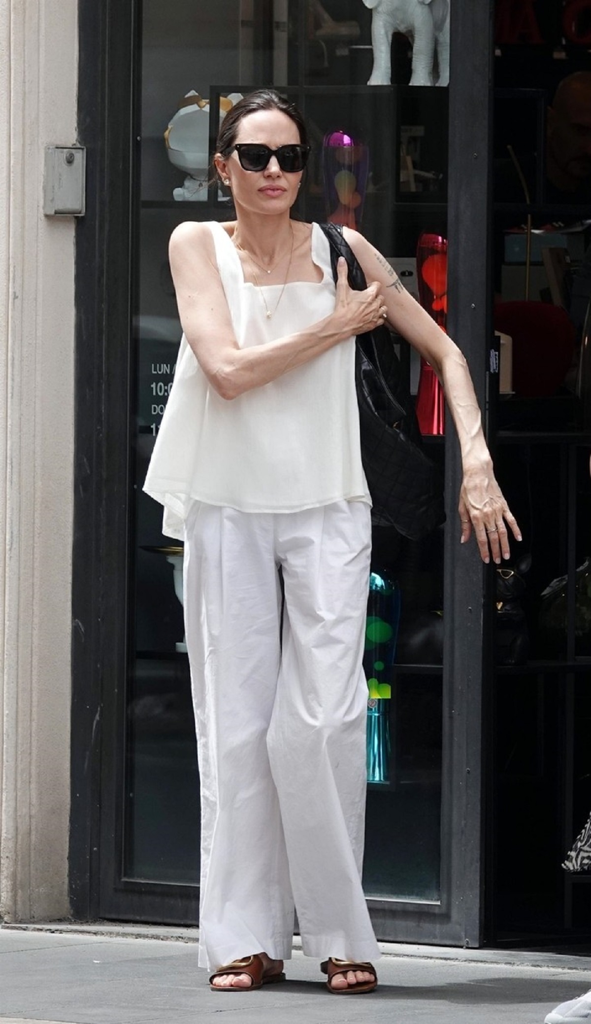 Angelina Jolie într-o ținută albă în timp ce iese din magazin și o așteaptă pe fiica sa, Zahara
