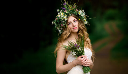 Fată frumoasă îmbrăcată în alb cu o coroană de flori pe cap și cu un buchet de flori în mână
