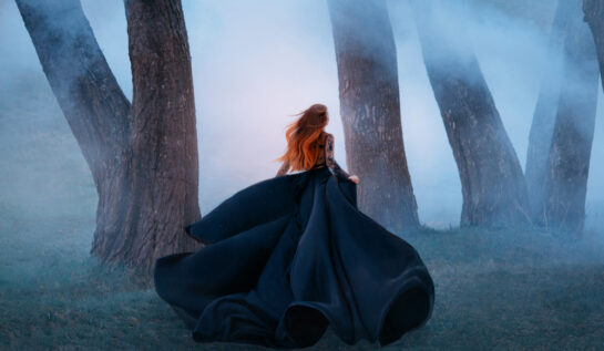 Fată frumoasă îmbrăcată într-o rochie lungă, neagră, aleargă prin pădure