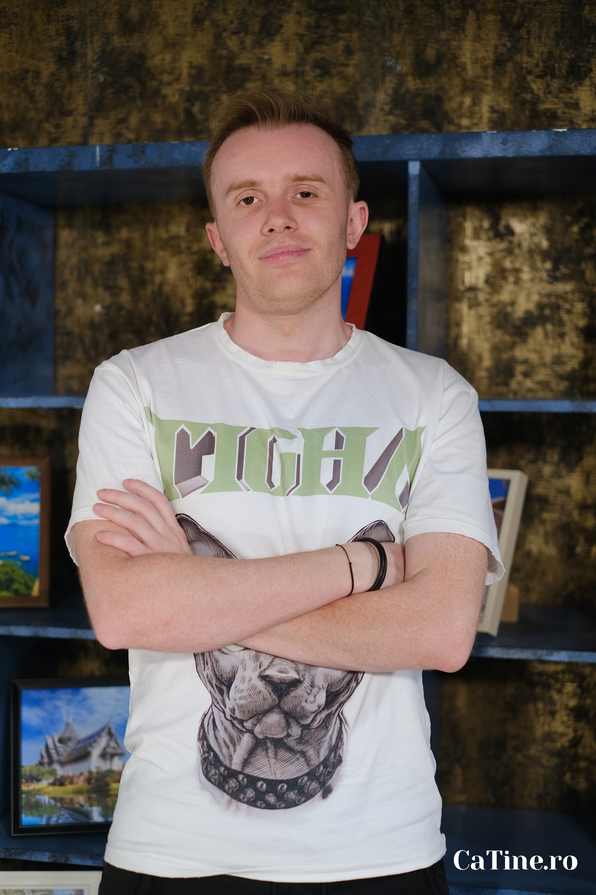 Ionuț Rusu într-un tricou alb în timp ce pozează cu brațele încrucișate pentru interviul CaTine.ro