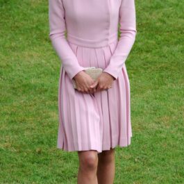 Kate Middleton într-o ținută roz cu o pălărie roz în timp ce ia parte la petrecerea ținută în grădinile palatului Buckingham din anul 2012