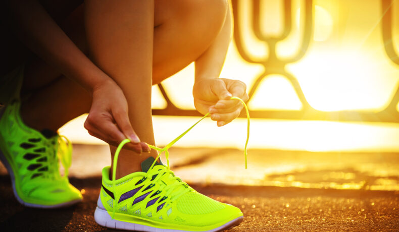 O femeie care își leagă șireturile pantofilor de alergat