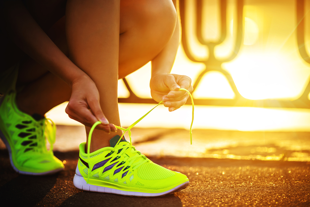 O femeie care își leagă șireturile pantofilor de alergat