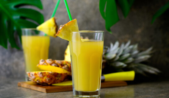 Suc de ananans într-un pahar transparent cu un pai verde