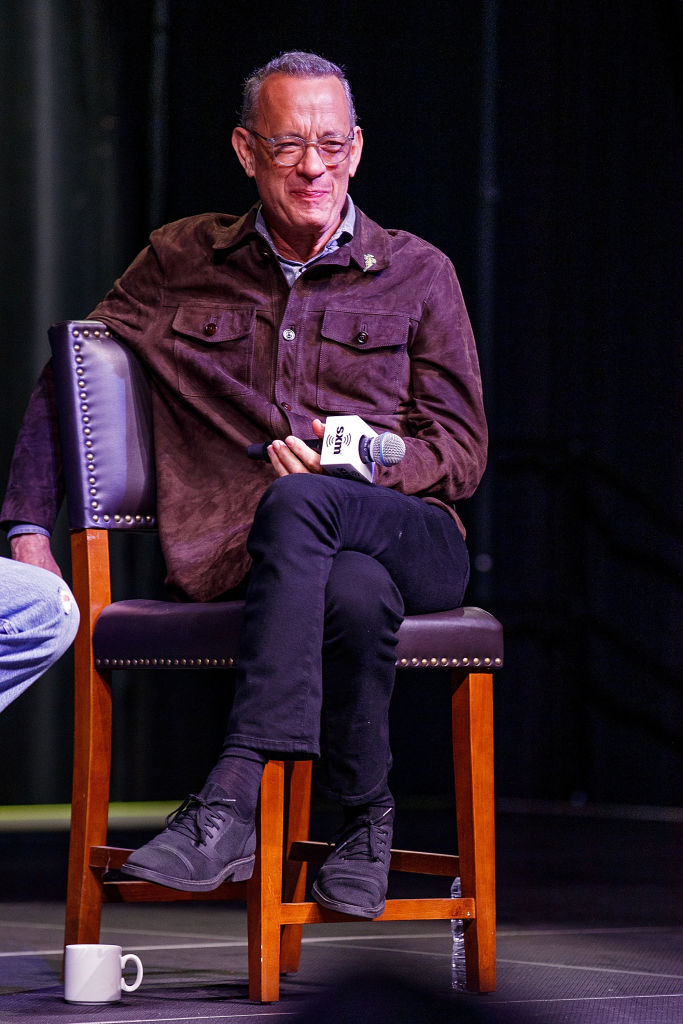 Tom Hanks, la o emisiune tv, îmbrăcat casual, pe un scaun