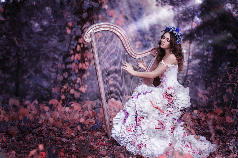 Fată frumoasă cu părul închis la culoare cântă la harpă
