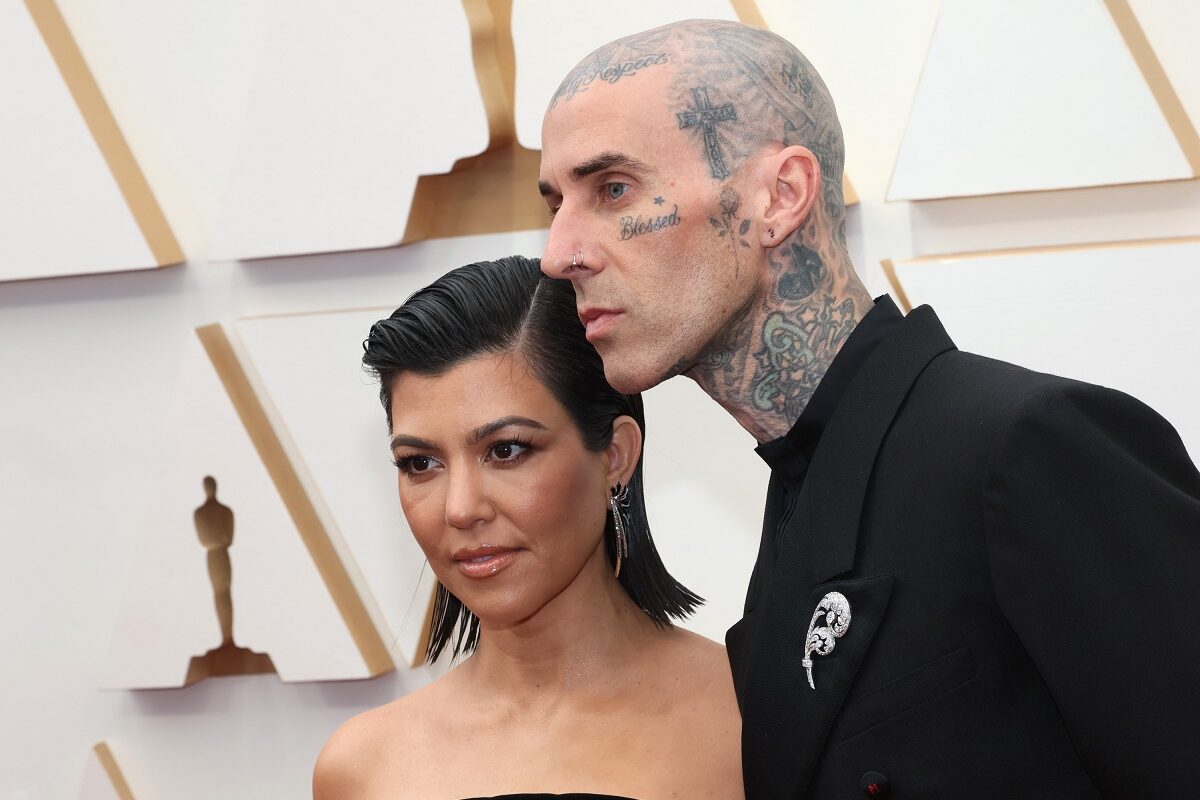 Kourtney Kardashian și Travis Barker în timp ce pozează împreună pe covorul roșu la Gala Premiilor Oscar 2022