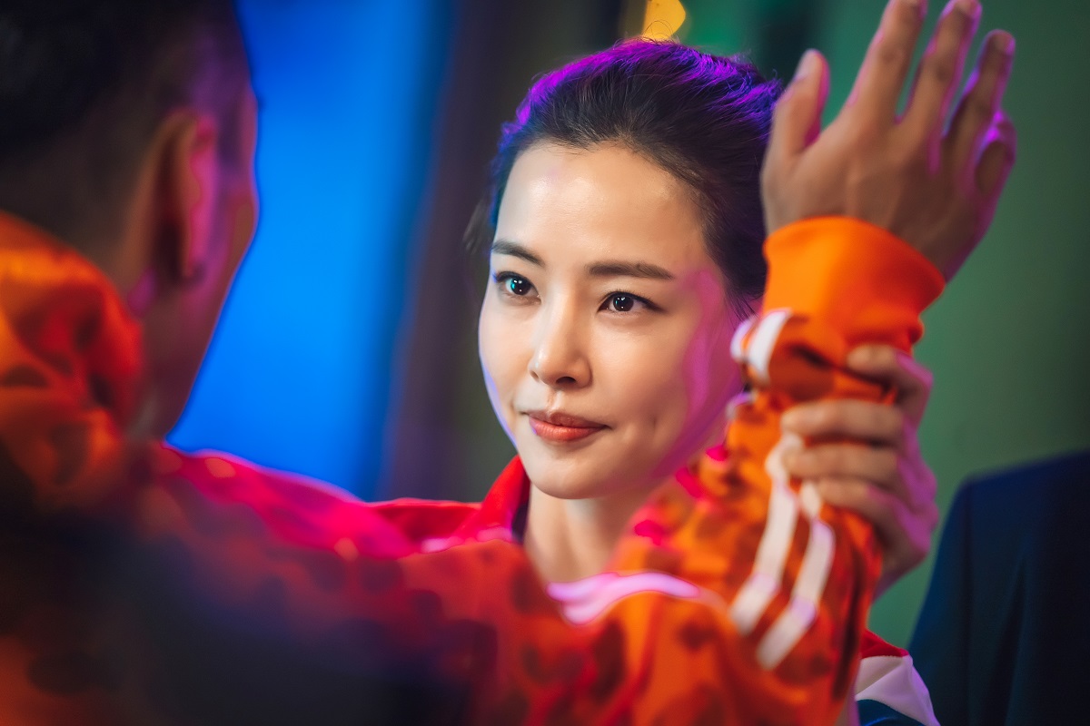 Actrița Lee Hanee într-un costum roșu în timp ce bate palma pe platourile de filmare ale serialului coreean One The Woman