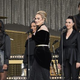 Adele pe scenă într-o rochie neagră alături de corul său în timp ce susține primul său concert cu public din ultimii cinci ani