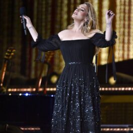 Adele într-o rochie neagră cu paiete și cu umerii goi în timp ce cântă pe scenă la primul său concert cu public din ultimii cinci ani