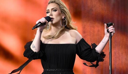 Adele într-o rochie enagră cu umerii goi în timp ce cântă la primul său concert cu public din ultimii cinci ani