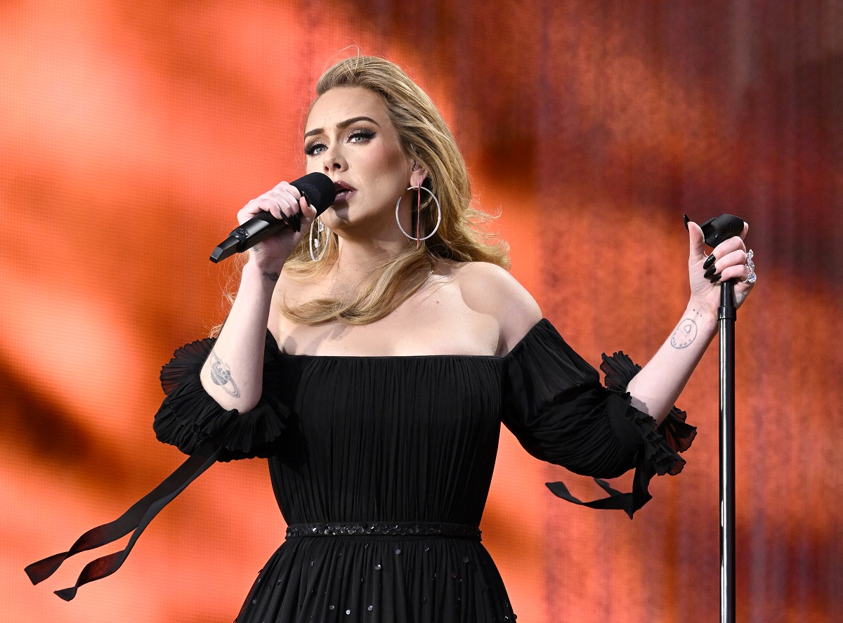 Adele într-o rochie enagră cu umerii goi în timp ce cântă la primul său concert cu public din ultimii cinci ani