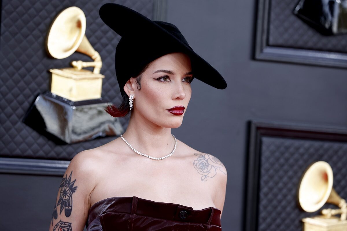 Halsey îmbrăcată într-o rochie cu umerii goi și o pălărie elegantă în timp ce pozează la Gala Premiilor Grammy 2022