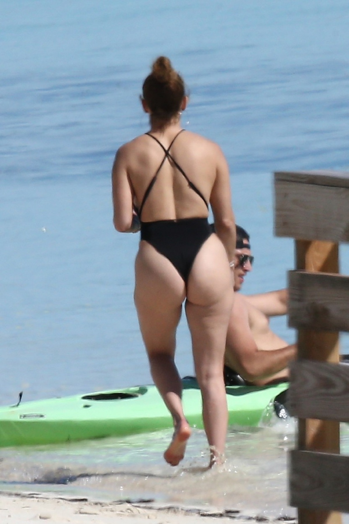 Jennifer Lopez cu spatele în timp ce pozează într-un costum de baie negru
