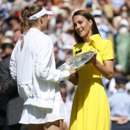 Elena Rybakina în timp ce acceptă trofeul de la Wimbledon de la Ducesa de Cambridge care poartă o rochie galbenă