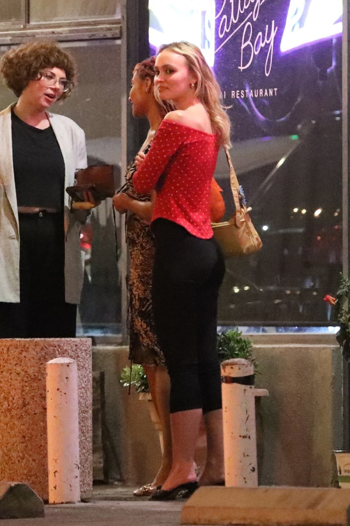 Lily-Rose Depp într-o bluză roșie cu buline și o pereche de pantaloni negri la un rstaurant din Los Angeles