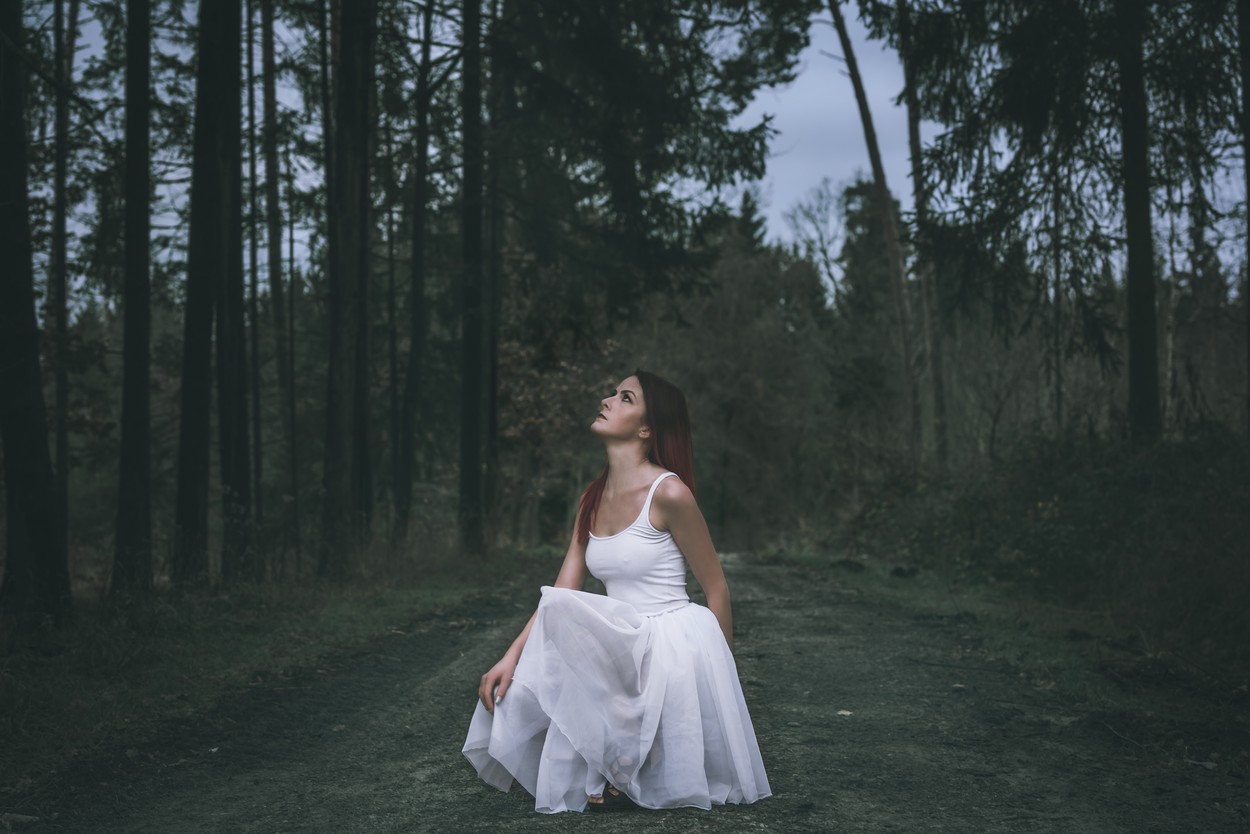 Fată frumoasă îmbrăcată într-o rochie albă în pădure