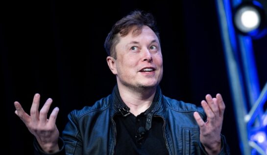 Elon Musk îmbrăcat la costum în timp ce ține o conferință de presă