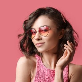 O femeie frumoasă care poartă o bluză roz și o pereche de ochelari de soare roz în timp ce își aranjează părul care este pe lista de tunsori bob care sunt în trend în 2022