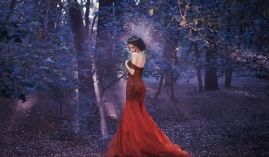 O femeie frumoasă în rochie roșie care se află într-o pădure violet pentru a ilustra una din cele trei zodii ghinioniste în ziua de 11 iulie 2022