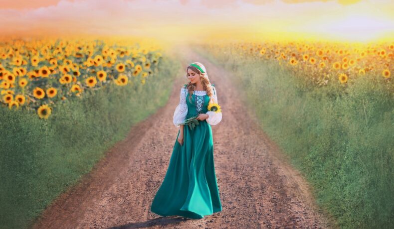 O femeie frumoasă care se plimbă pe un câmp cu floarea-soarelui pentru a ilustra una din cele trei zodii norocoase în ziua de 31 iulie 2022