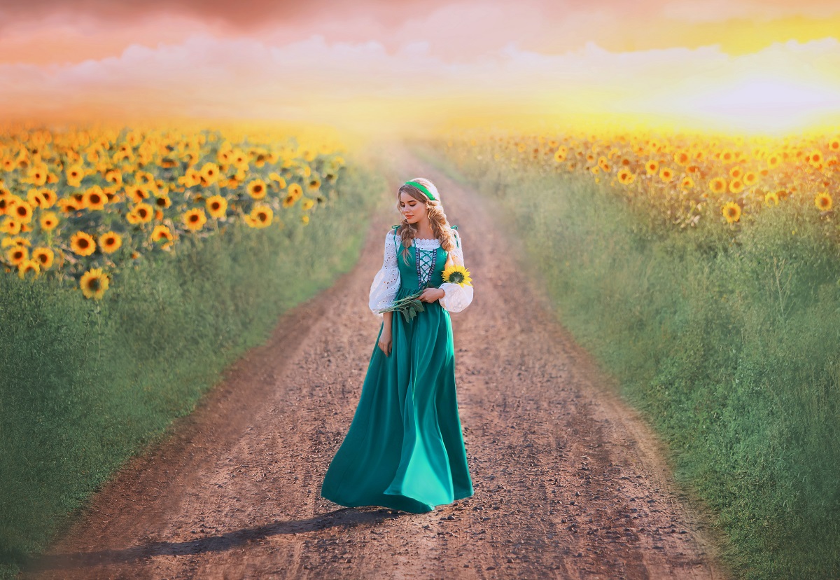 O femeie frumoasă care se plimbă pe un câmp cu floarea-soarelui pentru a ilustra una din cele trei zodii norocoase în ziua de 31 iulie 2022