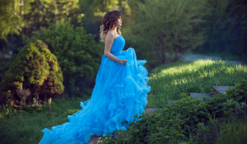 Fată frumoasă îmbrăcată într-o rochie lungă, albatră stă în pădure