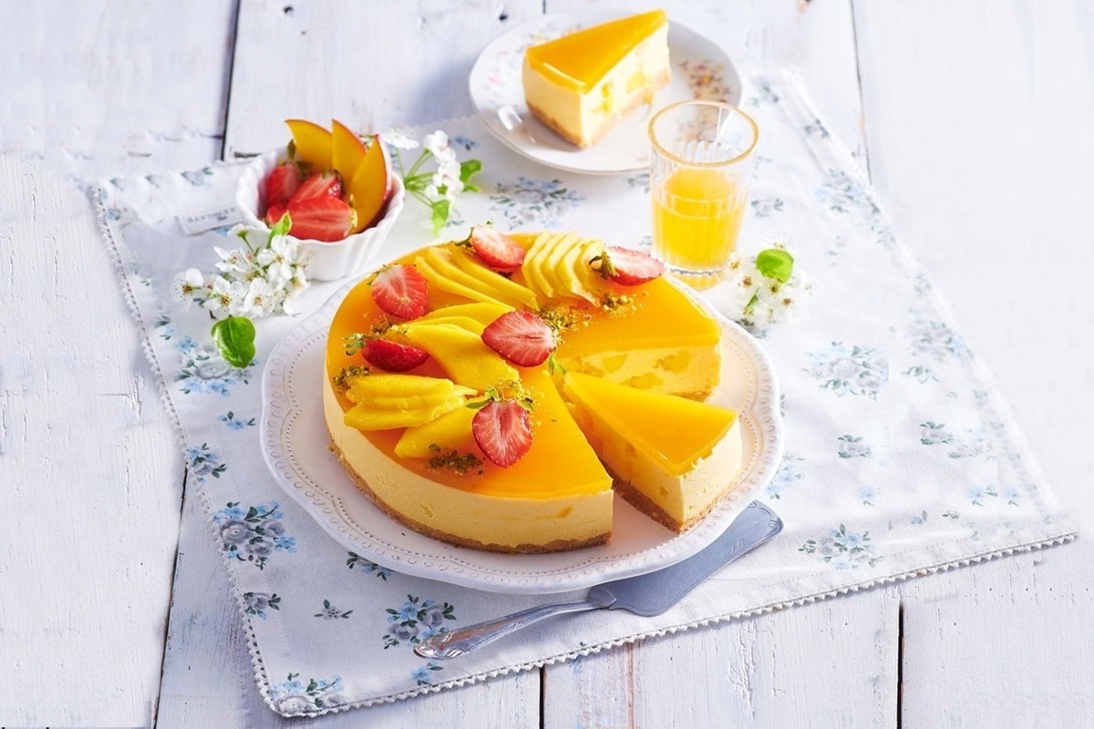 Cheesecake fără coacere cu mango porționat pe platou și pe farfurie
