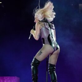 Lady Gaga fotografiată cu spatele într-un body gri în timp ce ține un cocnert în Londra