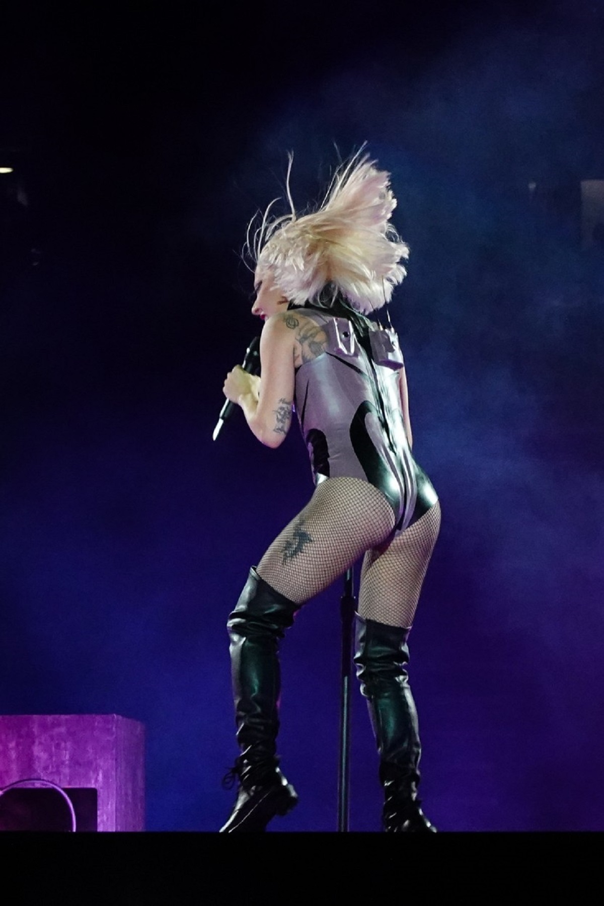Lady Gaga fotografiată cu spatele într-un body gri în timp ce ține un cocnert în Londra