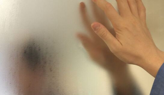 O femeie care dă cu degetul pe oglinda aburită din baie