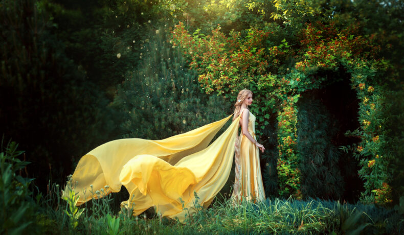 Fată frumoasă îmbractă într-o rochie lungă, galbenă intră pe o ușă din frunze