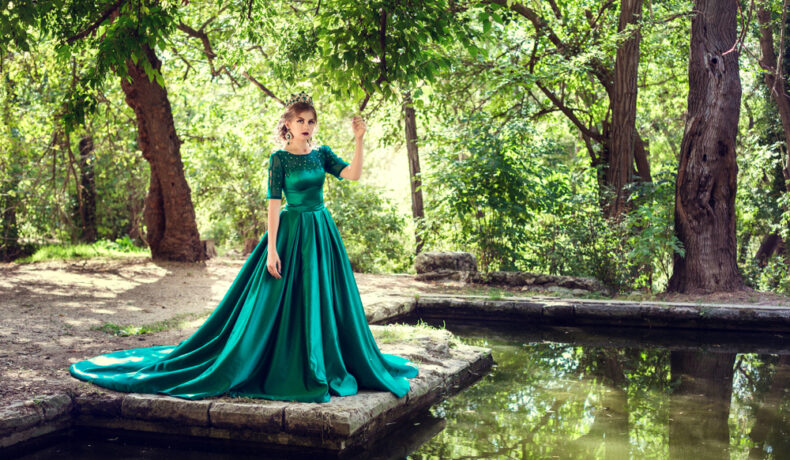 Fată frumoasă îmbrăcată într-o rochie verde, lungă se află în pădure