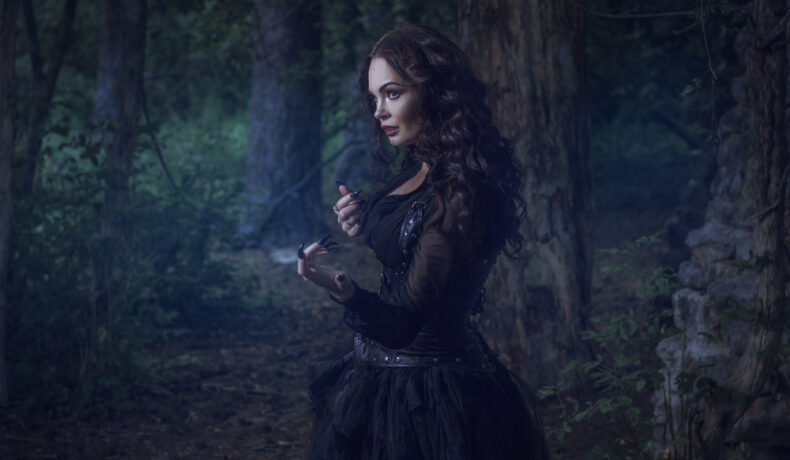 Fată frumoasă îmbrăcată în negru merge prin pădure