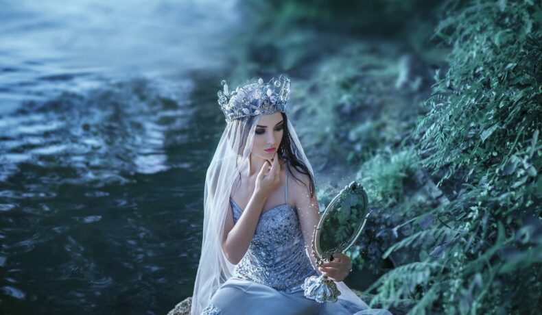 O femeie frumoasă care stă pe un lac și se privește în oglindă pentru a ilustra una din cele trei zodii ghinioniste în ziua de 15 august 2022