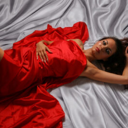 Femei frumoasă îmbrăcată în roșu stă întinsă într-un pat