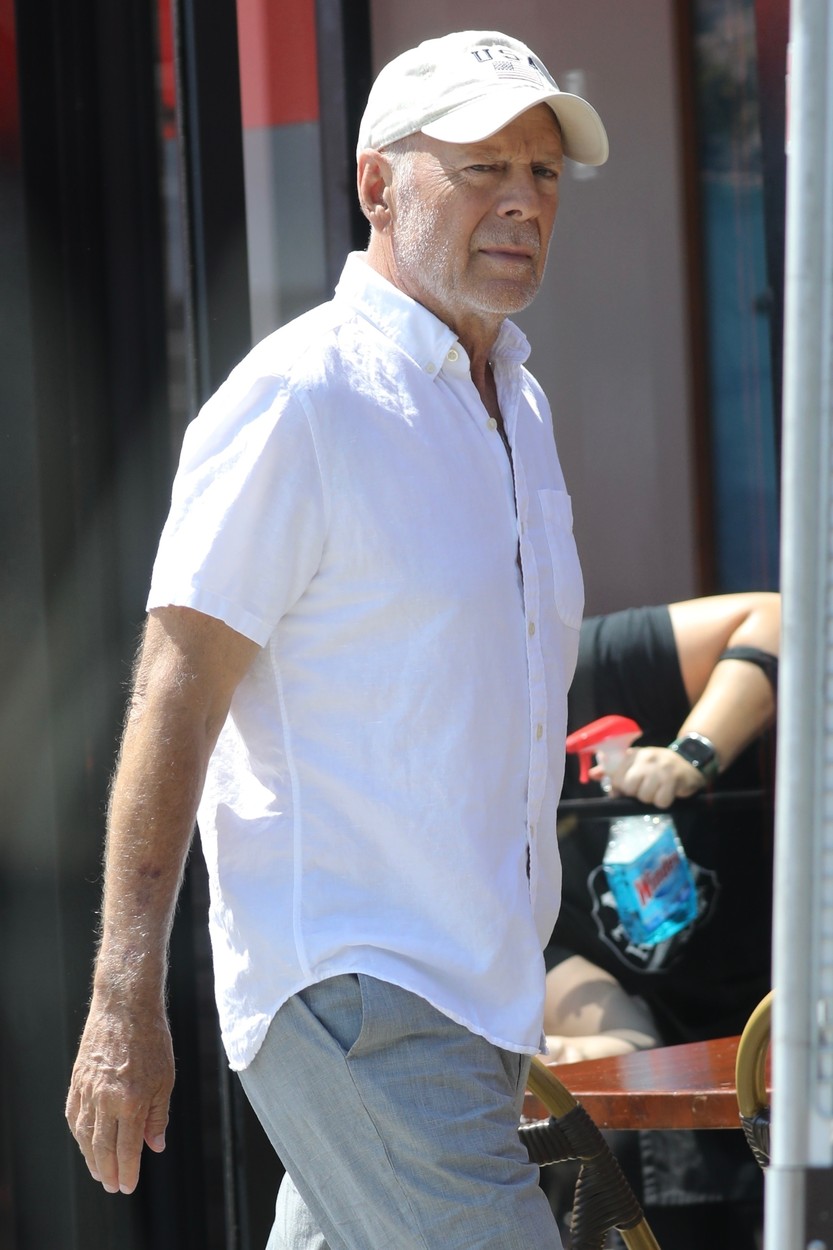 Bruce Willis, în cămașă albă, cu șapcă pe cap, în Los Angeles