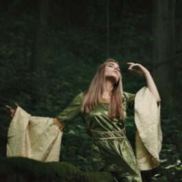 Fată frumoasă îmbrăcată într-o rochie de zână stă în pădure