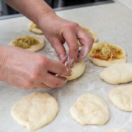 Femeie formând plăcinte cu varză