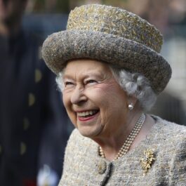 Regina Elisabeta a II-a într-un costum gri în timp ce poartă celebrul colier din perle la gât