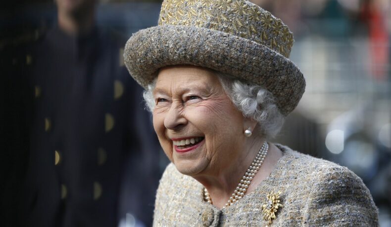 Regina Elisabeta a II-a într-un costum gri în timp ce poartă celebrul colier din perle la gât