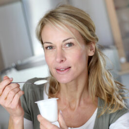 O femeie peste 40 de ani care mănâncă un iaurt