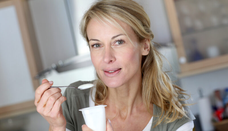 O femeie peste 40 de ani care mănâncă un iaurt