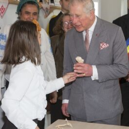 Regele Charles al III-lea în vizită în România în timp ce vorbește cu o fetiță