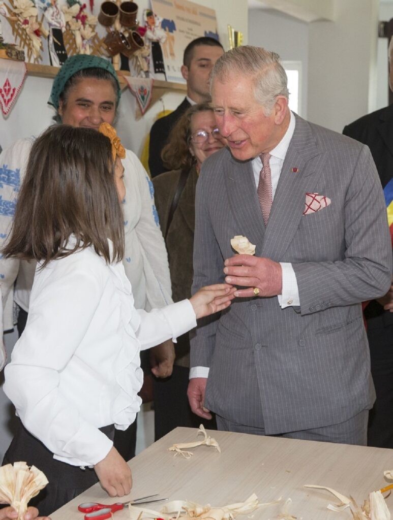 Regele Charles al III-lea în vizită în România în timp ce vorbește cu o fetiță