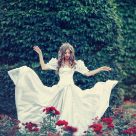 Fată frumoasă îmbrăcată într-o rochie lungă albă stă în pădure