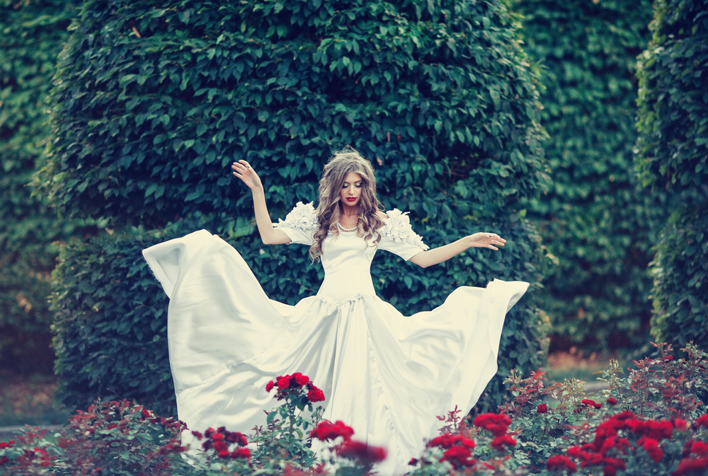 Fată frumoasă îmbrăcată într-o rochie lungă albă stă în pădure